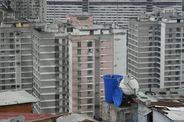 Người đàn ông cọ thùng chứa nước trên tầng thượng tại khu dân cư San Agustin, Caracas, ngày 17/5. Mời độc giả xem thêm video: Nền y tế Venezuela khủng hoảng vì bác sĩ rời bỏ đất nước (Nguồn video: VTC14)