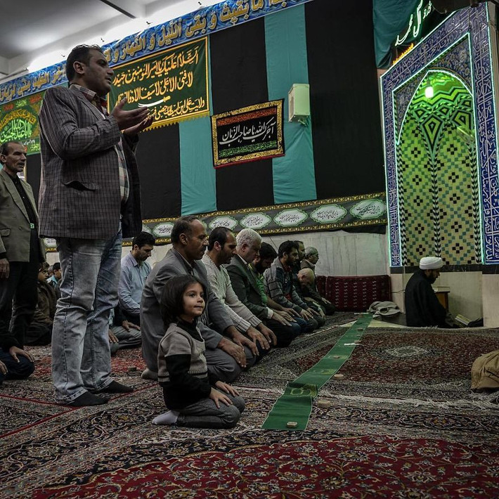 Hai cha con cùng mọi người cầu nguyện trong một nhà thờ Hồi giáo ở Iran.