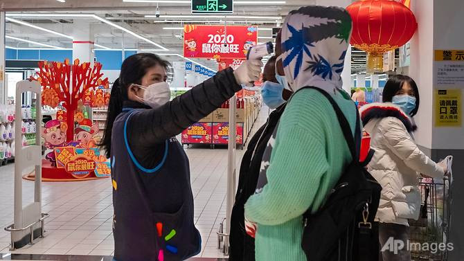 Nhân viên bán hàng đo thân nhiệt của khách ngay tại lối vào một cửa hàng Walmart ở Vũ Hán hôm 27/1. Ảnh: AP. Mời độc giả xem thêm video: Việt Nam phát hiện 3 hành khách đến từ ổ dịch viêm phổi cấp bị sốt (Nguồn video: VTC1)