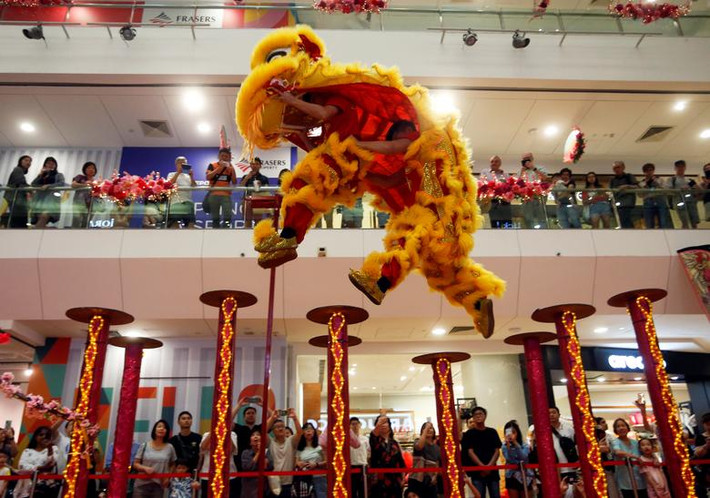 Mọi người chăm chú theo dõi màn trình diễn trong một trung tâm thương mại ở Singapore trước thềm năm mới. Ảnh: Reuters.