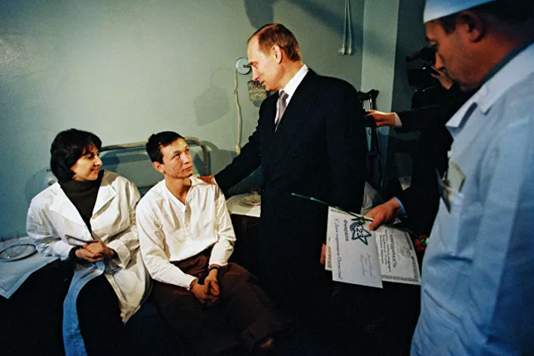 Ông Putin lên nắm quyền trong bối cảnh Nga rơi vào cuộc khủng hoảng kinh tế sâu sắc và bước vào cuộc chiến tranh Chechnya lần thứ hai nhằm đáp trả vụ ném bom các khu chung cư trên khắp nước Nga. Trong ảnh, Tổng thống Putin đến thăm bệnh viện quân y Volgograd, nơi các quân nhân đang điều trị, tháng 2/2000.