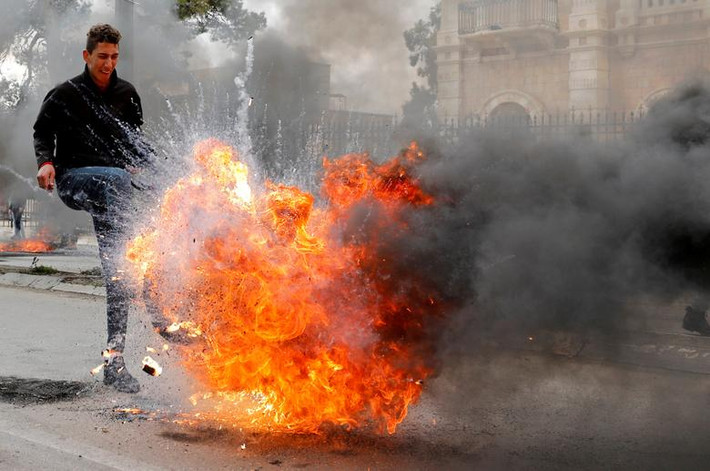 Một người Palestine đá chiếc lốp xe bị đốt cháy trên đường phố trong cuộc biểu tình phản đối "thỏa thuận thế kỷ" của Tổng thống Trump ở Bethlehem, Bờ Tây, ngày 29/1.