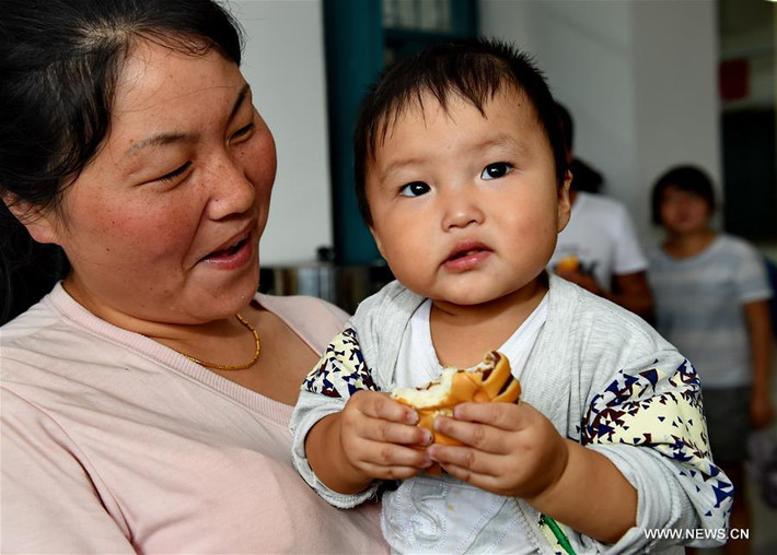 Một người phụ nữ bế con tại nơi tránh bão tạm thời.