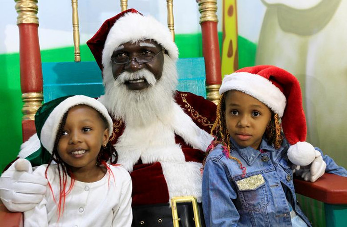 Ông già Noel Zedekiah Miyare, 56 tuổi, chụp ảnh với hai em nhỏ tại trung tâm thương mại ở Nairobi, Kenya, trong dịp lễ Giáng sinh năm 2019.