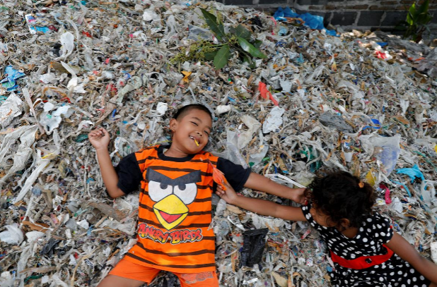 Các em nhỏ Indonesia chơi đùa trên một bãi rác trong làng.