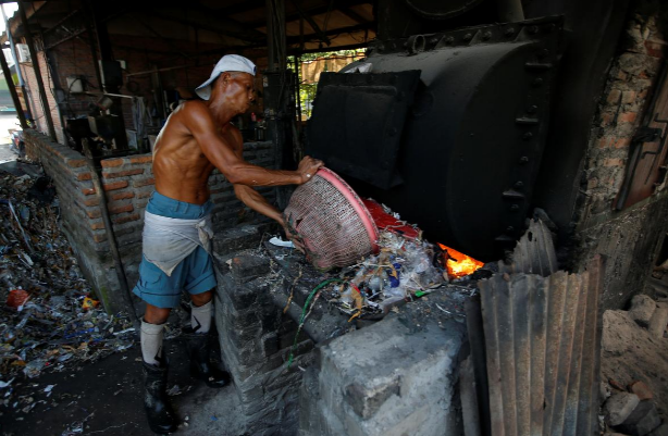 Một công nhân đốt rác trong nhà máy ở Sidoarjo, tỉnh Đông Java, hồi tháng 7/2019.