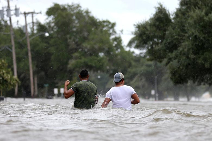 Người dân đi qua con phố ngập lụt ở Mandeville, Louisiana, Mỹ, sau khi bão Barry quét qua ngày 13/7/2019.