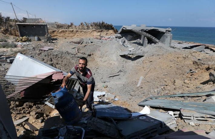 Người đàn ông Palestine kiểm tra một căn cứ quân sự ở phía nam Dải Gaza sau khi nơi này bị Israel không kích.