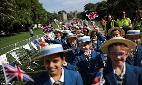 Các em nhỏ vẫy cờ khi đi bộ trên con đường Long Walk dẫn tới Lâu đài Windsor, nơi diễn ra đám cưới Hoàng gia của cặp đôi Harry-Markle vào ngày hôm nay 19/5. Ảnh: Reuters.