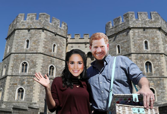 Một cặp đôi đeo mặt nạ Hoàng tử Harry và cô dâu Meghan Markle chụp ảnh lưu niệm bên ngoài Lâu đài Windsor. Ảnh: Reuters.