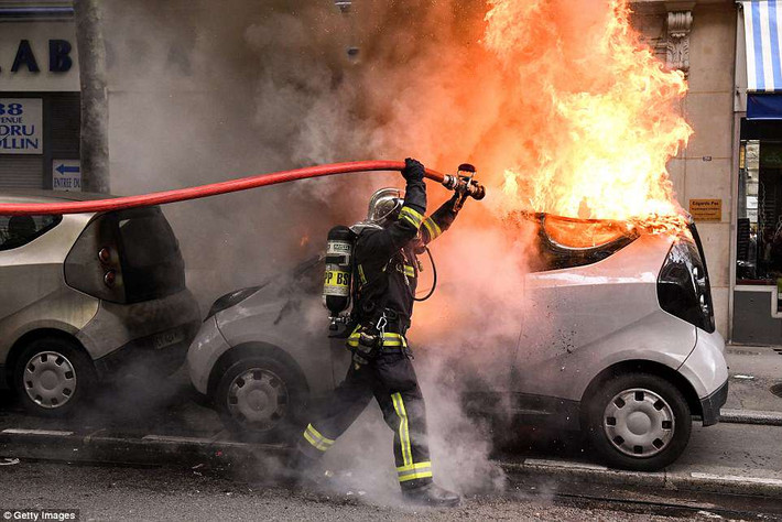 Lính cứu hỏa dập lửa cho chiếc ô tô đang bốc cháy trên đường phố thủ đô Paris ngày 1/5.