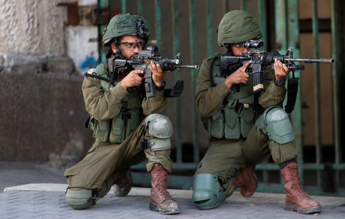 Các binh sĩ Israel chĩa súng về phía người biểu tình Palestine tại Hebron ở Bờ Tây hôm 11/5.