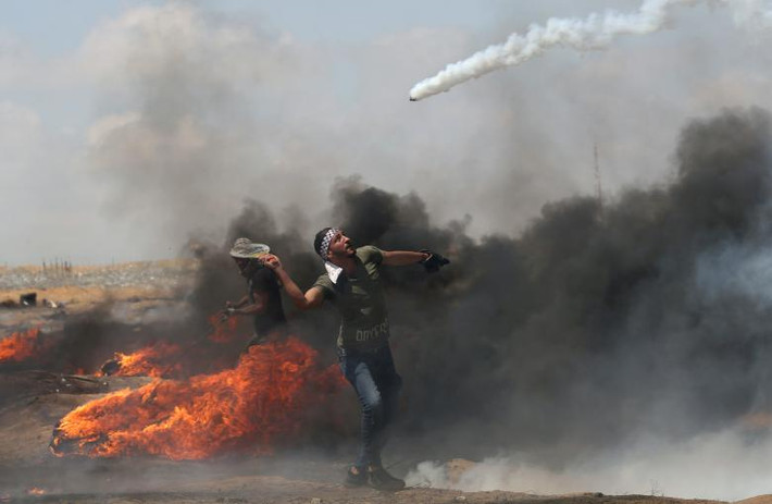 Một người biểu tình Palestine ném lựu đạn hơi cay về phía binh sĩ Israel trong cuộc đụng độ tại khu vực miền nam Dải Gaza hôm 11/5/2018.