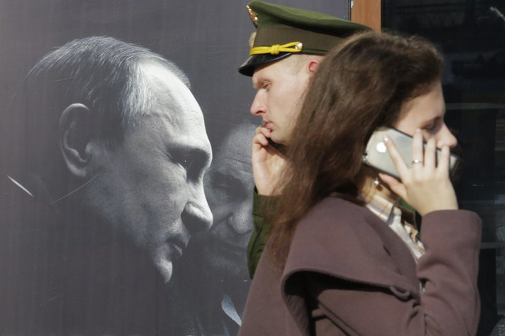 Người dân đi qua poster quảng cáo cuốn sách "Phỏng vấn Vladimir Putin" của nhà biên kịch, đạo diễn phim và nhà sản xuất người Mỹ Oliver Stone, được trưng bày tại một hiệu sách ở St. Petersburg. Từ ngày 7/5, ông Putin sẽ tiếp tục dẫn dắt nước Nga thêm 6 năm nữa trong bối cảnh Moscow đang căng thẳng với phương Tây và giữa những khó khăn về kinh tế.