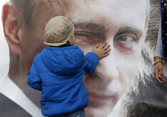 Một cậu bé đứng trước tấm áp phích in hình ông Putin ở St. Petersburg, Nga. "Ông ấy là một nhà cầm quyền khôn ngoan, không giải quyết ngay các vấn đề mà sẽ đề ra một đường hướng chiến lược và bổ nhiệm những người trẻ tài năng có thể thực hiện đường lối đó", Minchenko nói.