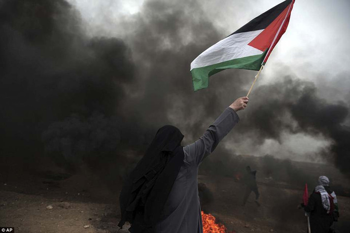 Người phụ nữ vẫy cờ Palestine khi tham gia biểu tình.