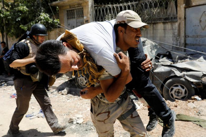 Một binh sĩ Iraq đưa một nhà báo bị thương ở chân trong cuộc giao tranh giữa lực lượng Iraq và phiến quân IS tới bệnh viện gần khu vực Thành cổ Mosul ngày 13/7/2017.