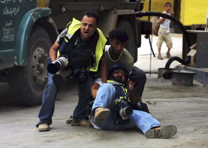 Phóng viên Abed Qmar Qusini người Palestine làm việc cho hãng tin Reuters ngã xuống đường sau khi bị thương trong cuộc đụng độ ở thành phố Nablus, Bờ Tây, ngày 3/5/2004. Mời độc giả xem thêm video: Những phóng viên chiến trường ở Syria (Nguồn: BBC/VTC14)