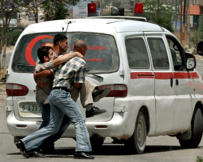 Người dân Palestine khiêng một phóng viên bị thương trong cuộc đụng độ giữa cảnh sát và phiến quân Palestine tại thành phố Jenin ở Bờ Tây ngày 24/5/2005.