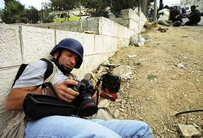 Yannis Behrakis, một phóng viên ảnh người Hy Lạp làm việc cho hãng thông tấn Reuters, nấp sau bức tường trong một cuộc đấu súng giữa lực lượng Israel và phiến quân Palestine ở thành phố Ramallah, Bờ Tây, hồi tháng 3/2001.
