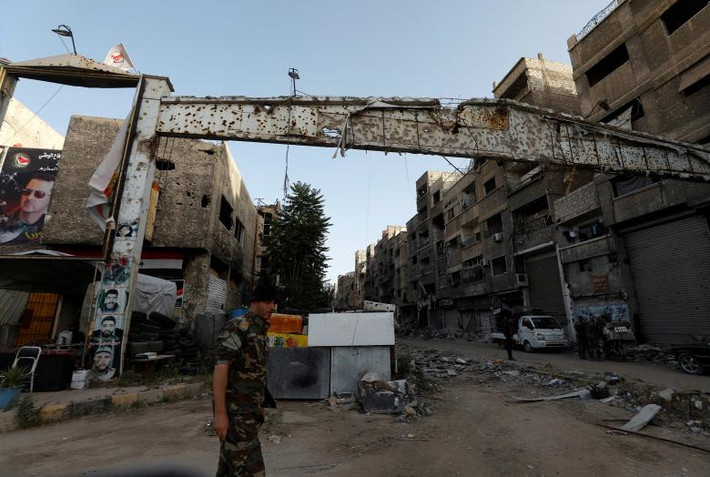 Một binh sĩ Syria đứng trước lối vào Trại Yarmouk ở Damascus ngày 21/5.