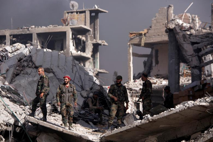 Các binh sĩ Syria đứng giữa đống đổ nát của những tòa nhà bị phá hủy ở al-Hajar al-Aswad hôm 21/5.