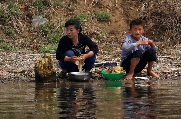 Người phụ nữ Triều Tiên và một em nhỏ rửa rau bên bờ sông Áp Lục.