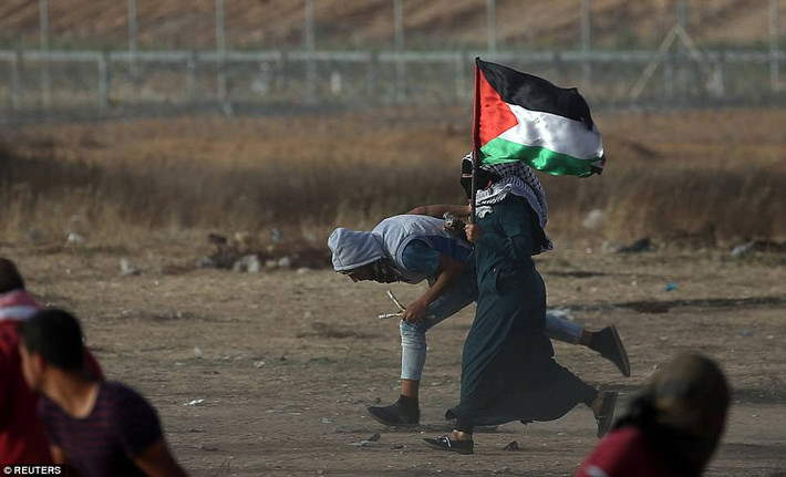 Người phụ nữ cầm cờ Palestine tham gia cuộc biểu tình ở biên giới Israel-Gaza. Ảnh: Reuters.