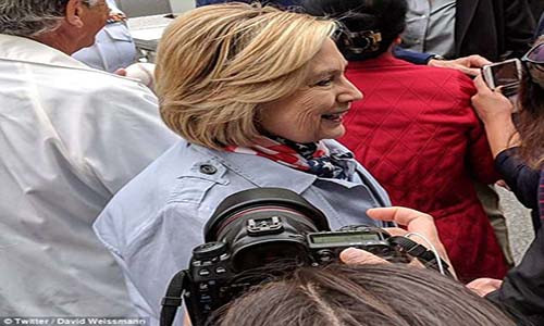 Trong buổi diễu hành, bà Clinton mặc chiếc áo khoác rộng và quàng khăn. Đáng chú ý, phần áo phía sau lưng vị cựu ngoại trưởng 70 tuổi phồng lên bất thường. Ảnh: Twitter.