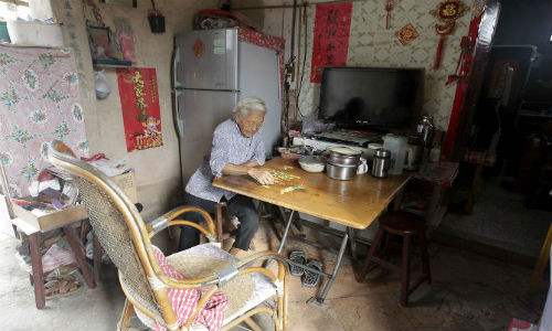 Một cụ già đang ngồi chơi bài trong bếp ở làng Guningtou, Kim Môn, ngày 7/9/2015.