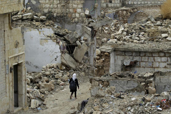 Một nữ sinh đi bộ qua tòa nhà đổ nát ở thị trấn Maaret al-Numan, Syria, ngày 28/10.