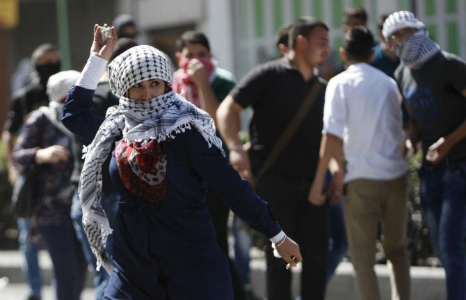 Một phụ nữ Palestine ném đá vào binh sĩ Israel ở thành phố Hebron ngày 13/10.