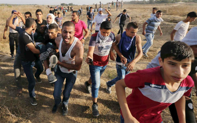 Một người biểu tình Palestine bị thương sau khi trúng đạn của binh sĩ Israel ở gần khu vực biên giới Israel và Dải Gaza hôm 13/10.