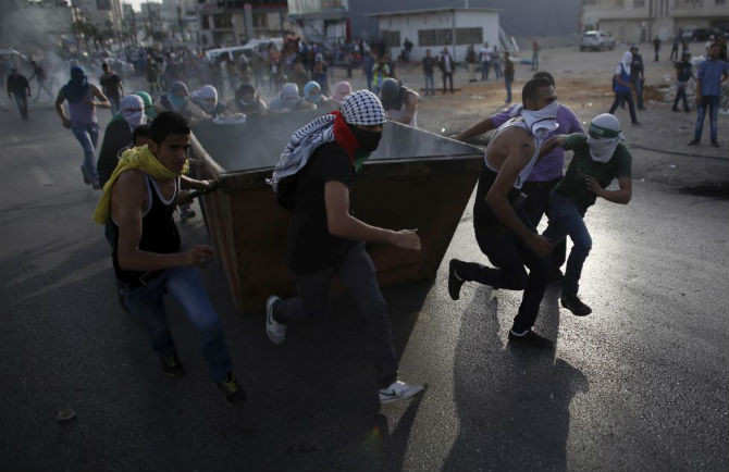 Những người biểu tình Palestine đẩy một thùng rác trong cuộc xung đột với binh sĩ Israel gần khu định cư Do thái Bet El ngày 13/10.