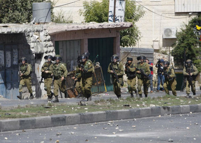 Binh sĩ Israel vào vị trí trong cuộc đụng độ với người biểu tình Palestine ở thành phố Hebron, Bờ Tây ngày 13/10.