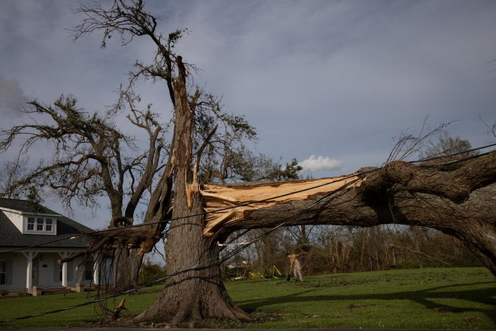 Kurt Charpentier quét lá cây trước nhà ở Bourg, Louisiana, ngày 30/8.