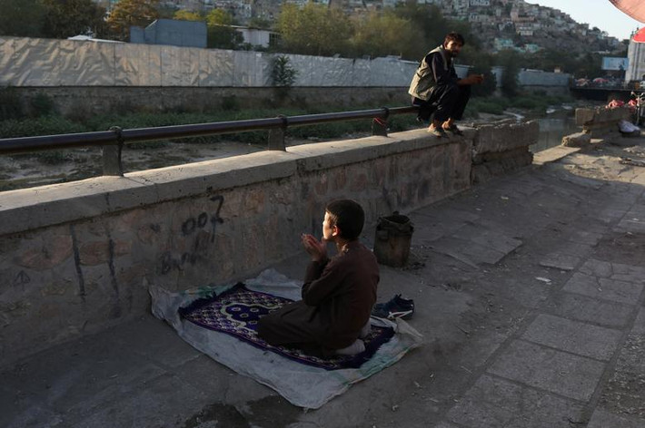 Bé trai Afghanistan cầu nguyện trên một con phố ở thủ đô Afghanistan.