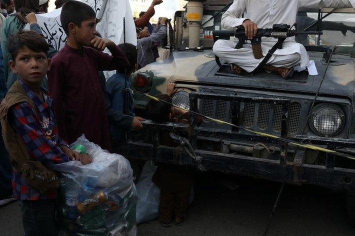 Em nhỏ Afghanistan đứng nhìn vũ khí của một chiến binh Taliban ở Kabul, ngày 1/9.