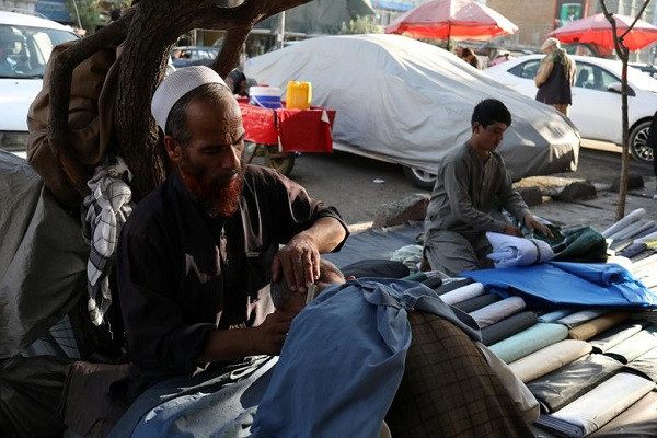 Thợ cắt tóc người Afghanistan cắt tóc cho một đứa trẻ trên đường phố ở Kabul.