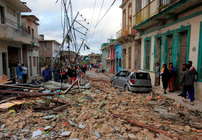 Người dân đi qua con phố đổ nát ở La Habana hôm 28/1.