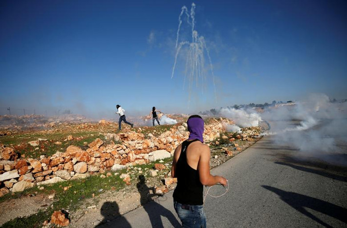Người biểu tình Palestine tháo chạy trong làn khói hơi cay mù mịt tại ngôi làng Nabi Saleh ở Bờ Tây ngày 13/1.