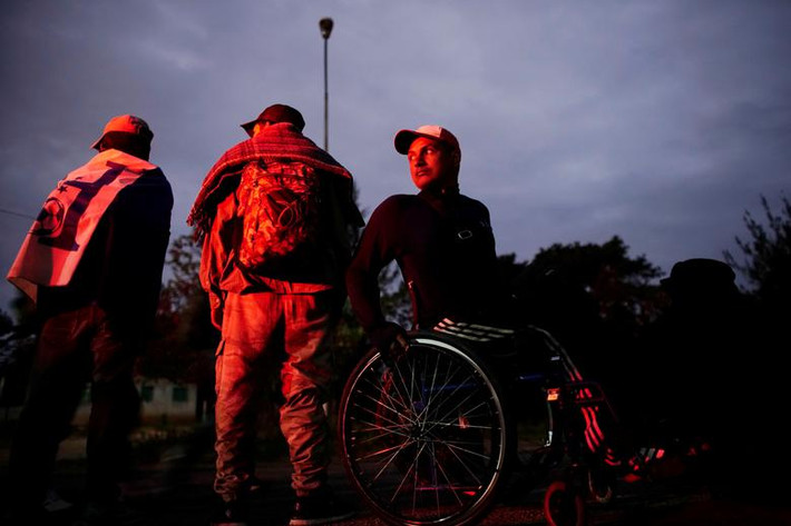 Paraplegic Kevin Dominguez (phải) đến từ Honduras ngồi trên xe lăn khi chờ đi nhờ xe tại Matias Romero ngày 24/1.