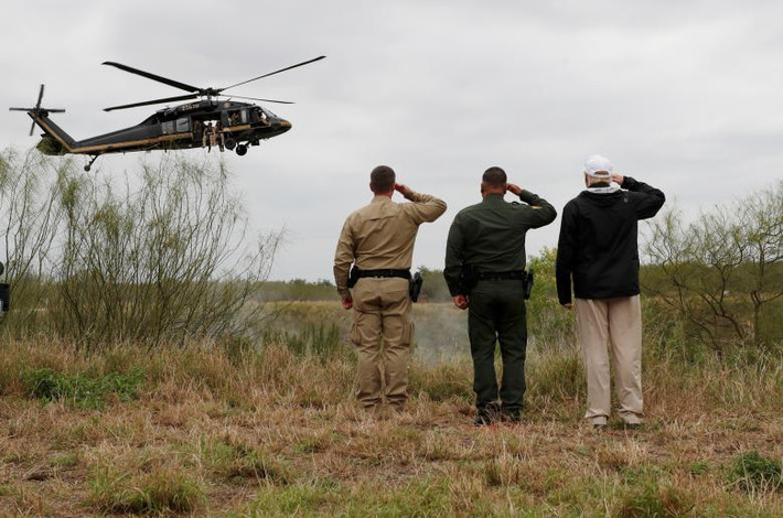 Tổng thống Trump giơ tay chào một chiếc trực thăng của lực lượng biên phòng Mỹ khi nó bay qua sông Rio Grande ở Mission ngày 10/1.