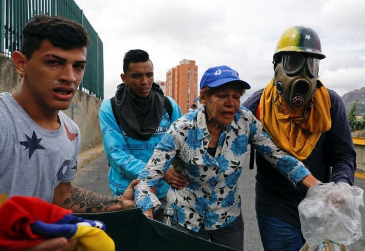 Một số người biểu tình được đưa đi sau khi trúng hơi cay trên đường phố Caracas ngày 23/1.