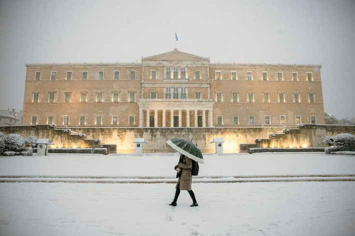 Người phụ nữ che ô đi dưới trời mưa tuyết ở Athens, Hy Lạp, ngày 16/2.