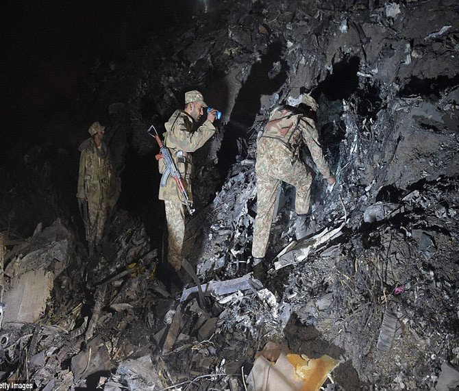 Các binh sĩ Pakistan tìm kiếm thi thể nạn nhân tại khu vực hiện trường máy bay rơi ở làng Saddha Batolni, huyện Abbottabad, tỉnh Khyber Pakhtunkhwa.