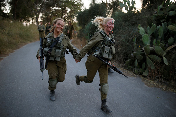 Các nữ binh sĩ Israel thuộc lữ đoàn Tìm kiếm và Cứu hộ nắm tay nhau khi tham gia buổi tập luyện ở khu rừng Ben Shemen, gần thành phố Modi.