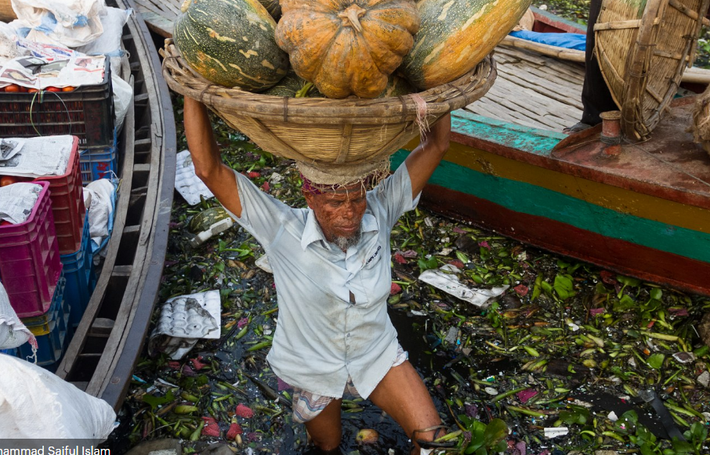 Một người công nhân xắn cao quần khi lội qua dòng nước ô nhiễm ở Dhaka, Bangladesh.