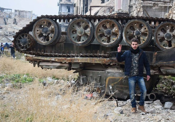 Người đàn ông chụp ảnh trước một chiếc xe tăng bị hư hại trong các cuộc giao tranh ở Aleppo.