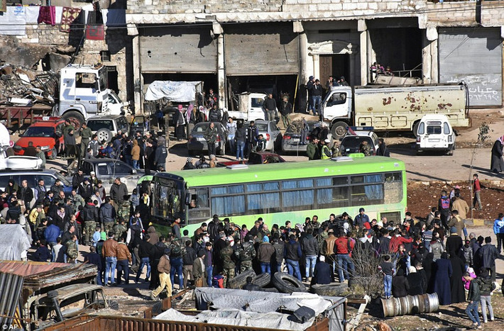 Đông đảo người dân tập trung xung quanh chiếc xe buýt xanh của chính phủ Syria tại Aleppo chờ lên xe tới Idlib.